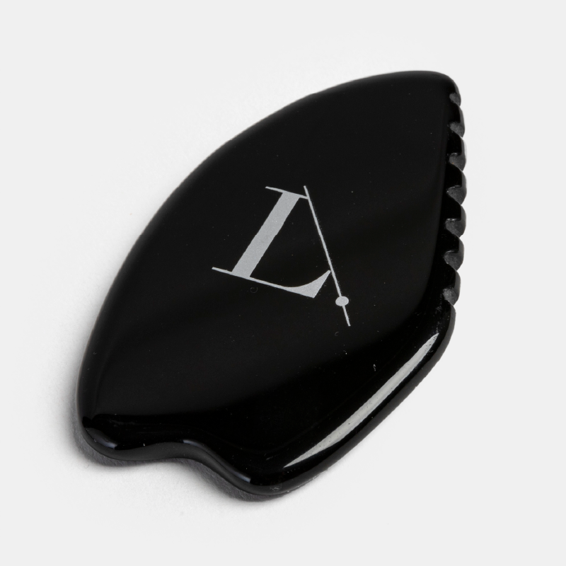 Gros plan sur le Gua Sha en obsidienne noire de la marque Limelife by Alcone, avec son logo blanc, posé sur un fond blanc.