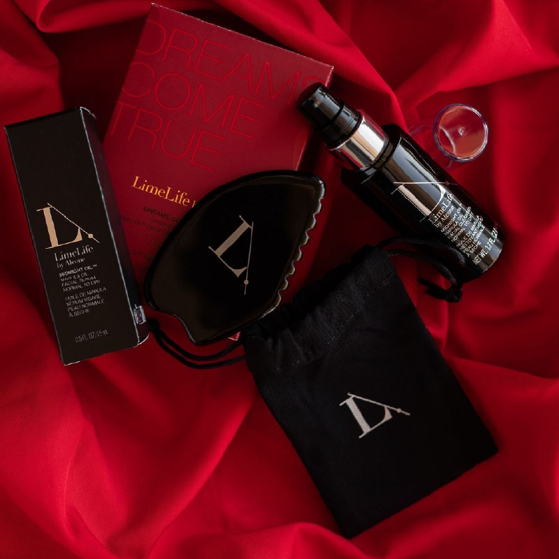 Mise en scène du Gua Sha en obsidienne et de sa pochette, présentés avec d'autres produits de soin Limelife sur un tissu rouge satiné.