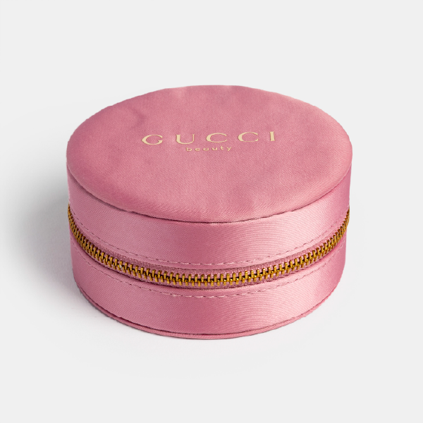 Vue d'ensemble de la boîte à bijoux Gucci, mettant en valeur sa forme ronde, sa couleur rose poudré et sa texture satinée issue de polyester recyclé.
