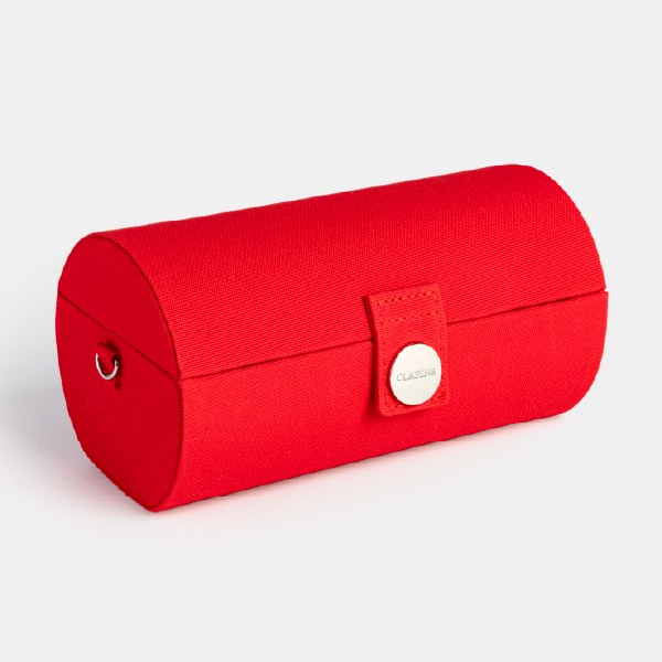 Vue de trois-quarts du coffret rouge Clarins fermé, montrant sa forme cylindrique de minaudière et son fermoir.