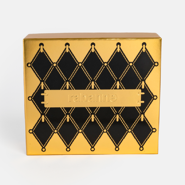 Vue de face du coffret cadeau Rabanne fermé. Le design présente un motif de losanges noirs sur un fond doré métallique, avec une plaque centrale siglée "rabanne".