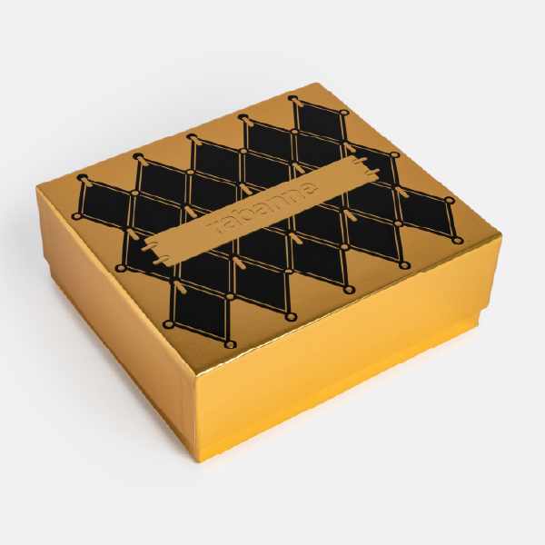 Vue de trois-quarts du coffret cadeau Rabanne doré et noir, montrant le dessus et le côté de la boîte fermée.