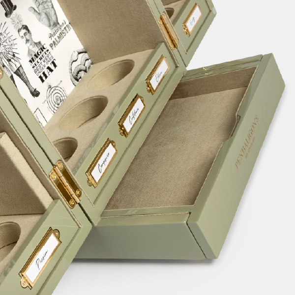 Vue en angle du coffret Penhaligon's ouvert, montrant le tiroir inférieur doublé de suédine et les compartiments de rangement pour les potions.