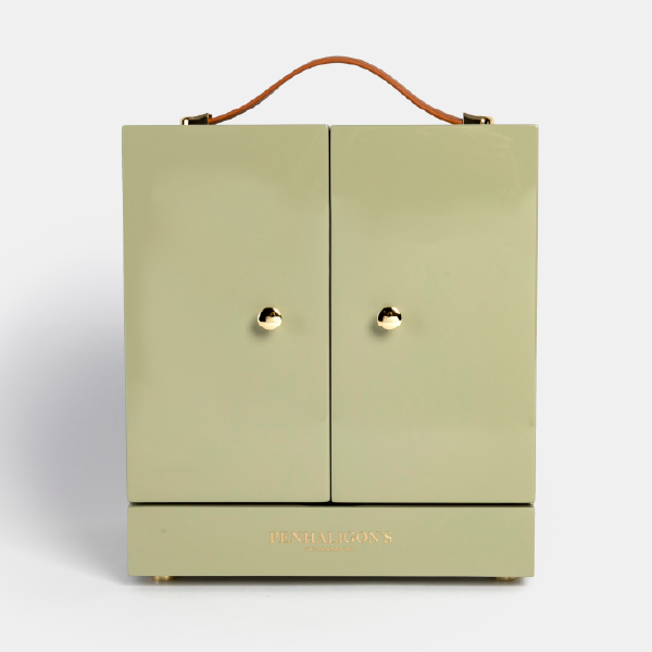 Vue de face de la mallette-coffret Penhaligon's fermée, en bois laqué vert sauge, avec ses deux portes à boutons dorés et sa poignée.