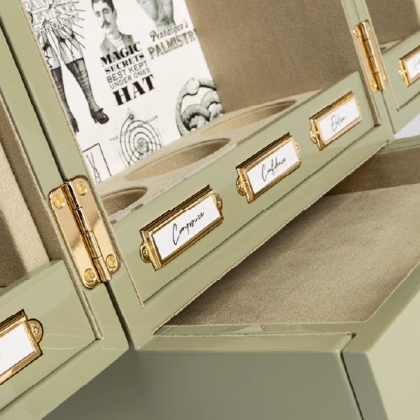 Gros plan sur l'intérieur du coffret Penhaligon's, mettant en évidence les porte-étiquettes en métal doré, les charnières et la doublure en suédine.