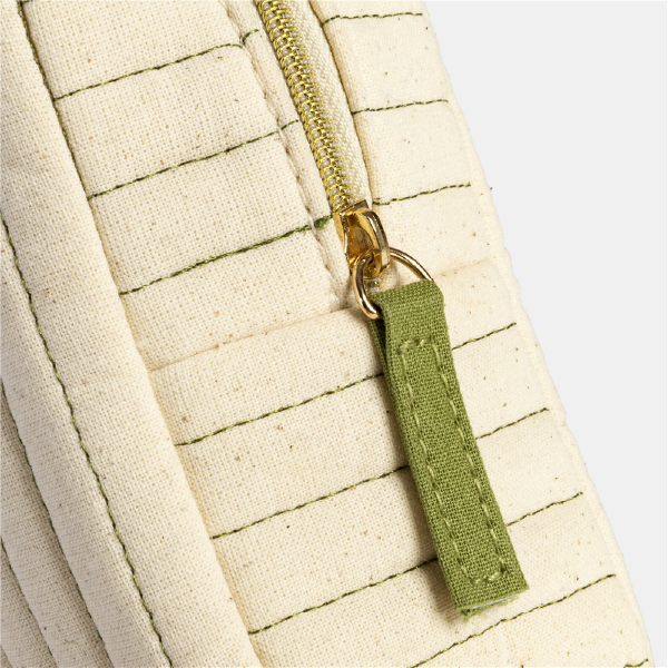 Gros plan sur la fermeture éclair dorée et la tirette en tissu vert de la trousse Douglas, illustrant les finitions du produit.