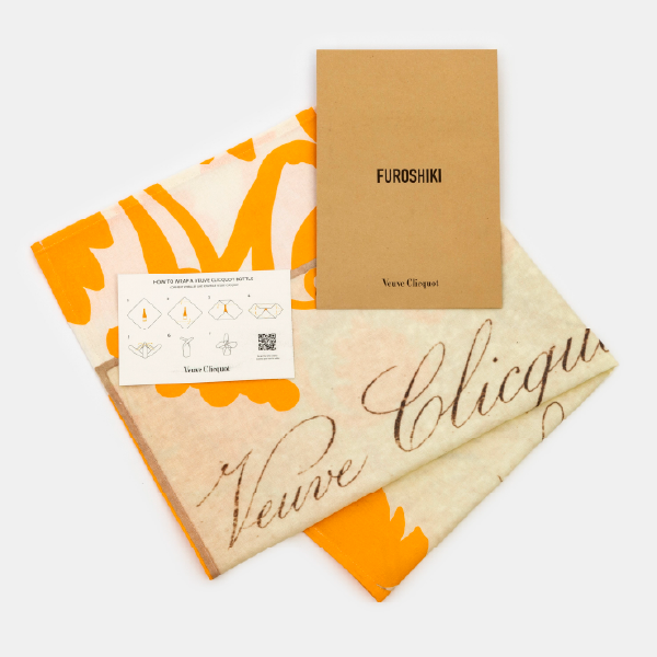 Le furoshiki Veuve Clicquot plié, accompagné de sa notice explicative et de son étui en carton.