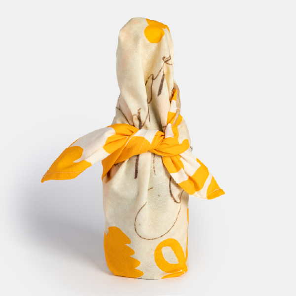 Vue d'une bouteille entièrement emballée dans le furoshiki Veuve Clicquot, noué sur le dessus.