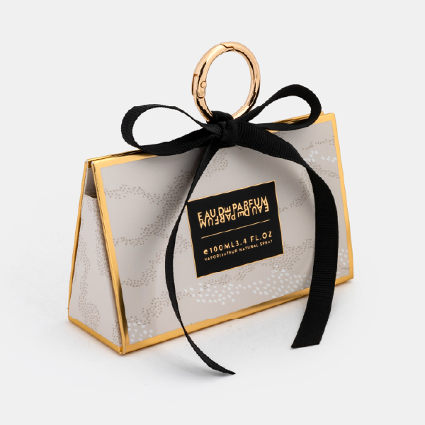 Vue de trois-quarts du mini bag fermé à motif pointillé, montrant sa forme trapézoïdale et ses bordures dorées.