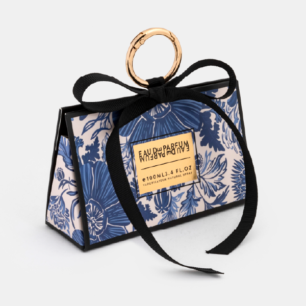 Vue de trois-quarts du mini bag fermé à motif floral bleu, montrant sa forme trapézoïdale et son ruban noué.