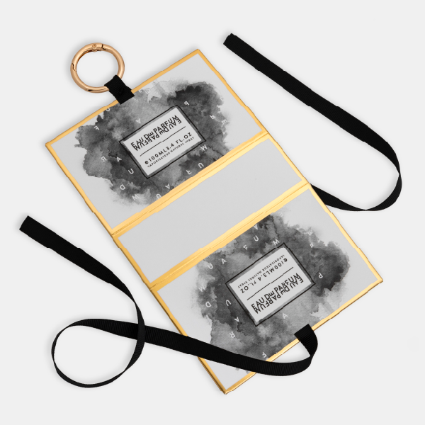 Le mini bag à motif aquarelle déplié à plat, montrant sa structure avec des bordures dorées, le ruban noir et l'anneau mousqueton.