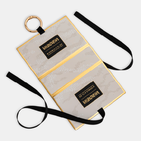 Le mini bag à motif pointillé déplié à plat, révélant sa conception pliable, son ruban de fermeture et son anneau mousqueton.