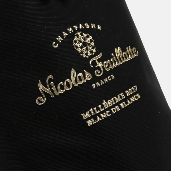 Gros plan du logo "Nicolas Feuillatte" en marquage à chaud doré sur la texture du velours noir du pochon.