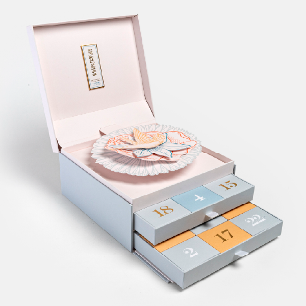 Calendrier de l'Avent pop-up ouvert, montrant la fleur en papier au centre et les deux tiroirs contenant les 24 cases numérotées.