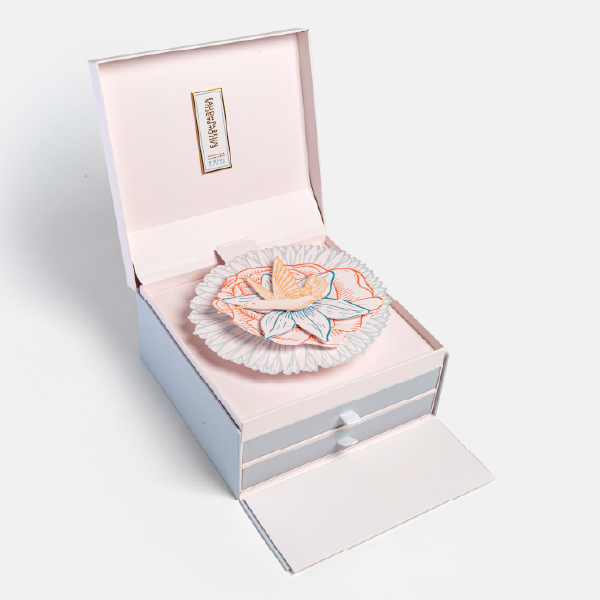 Calendrier de l'Avent ouvert avec son panneau avant rabattu, cachant les deux tiroirs. Le pop-up floral est visible au centre.