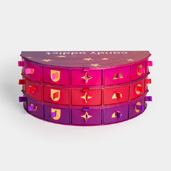 Vue de face du calendrier de l'Après avec ses trois niveaux empilés et fermés, montrant l'alignement des tiroirs et le dégradé de couleur du rose au violet.