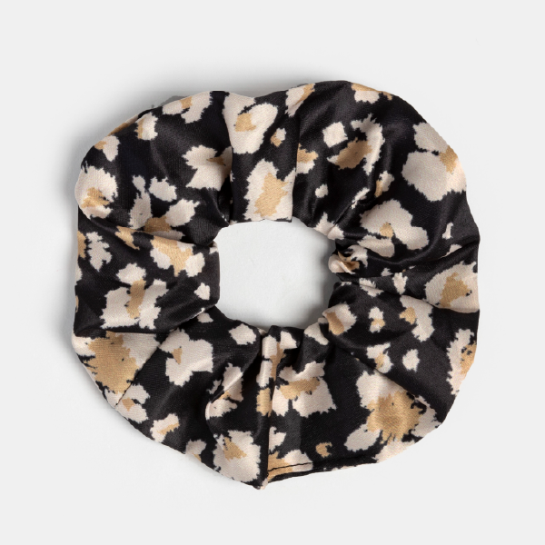 Le chouchou en tissu avec un motif léopard noir et beige.