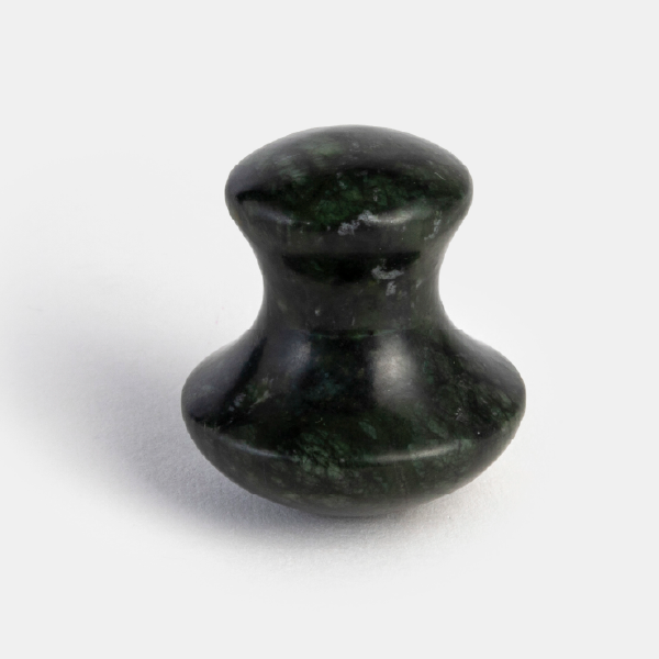 La pierre de massage Gua Sha en jade vert foncé, en forme de champignon, pour le soin du visage.