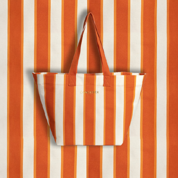 Sac de plage Lancaster en coton bio à rayures orange et blanches, présenté sur un fond assorti pour un effet graphique.