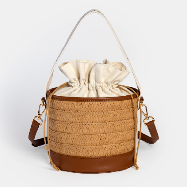 Sac seau Fresh en paille de papier tressée, avec base et finitions en PU écologique marron, pochon intérieur en coton recyclé et anse blanche.