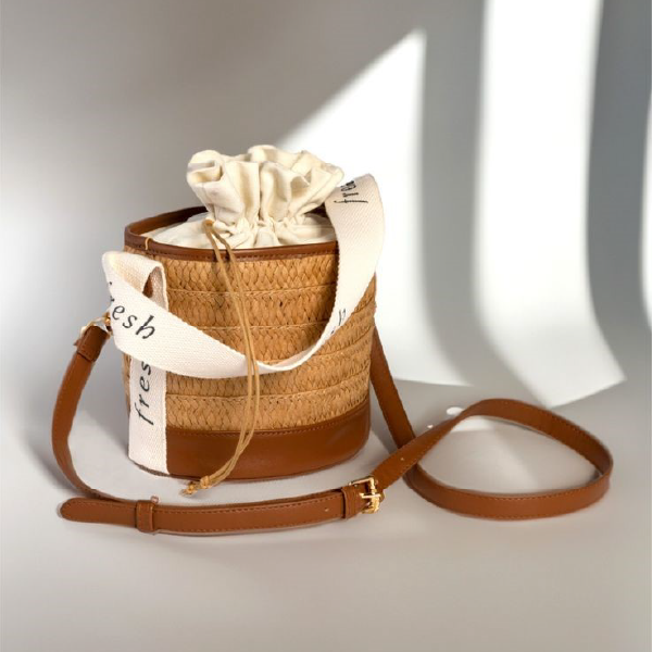 Sac seau tendance Fresh Beauty avec sa bandoulière amovible en PU marron, posé dans une ambiance lumineuse qui souligne ses matières naturelles.