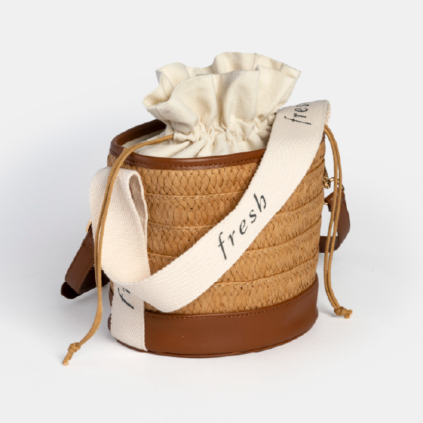 Vue de trois-quarts du sac seau Fresh, illustrant sa forme structurée, son pochon de fermeture pratique et sa double option de porté (anse et bandoulière).
