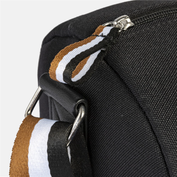 Gros plan sur les finitions du sac Hugo Boss, montrant la tirette du zip avec son ruban tricolore et l'attache de la bandoulière en métal.