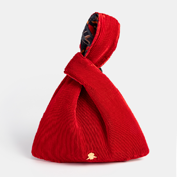 Sac à main "Kinchaku" Sisley en satin plissé rouge vibrant, avec son anse nouée et le monogramme Sisley en métal doré.