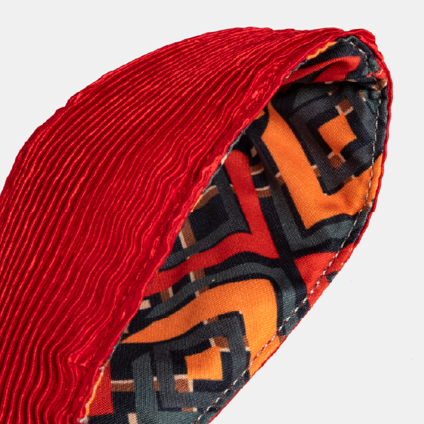 Gros plan sur l'intérieur de l'anse du sac rouge, montrant la doublure contrastante avec son motif géométrique orange et noir.