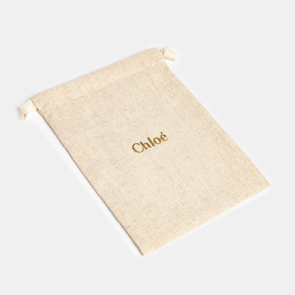 Pochon Chloé en lin et viscose posé à plat pour montrer sa forme rectangulaire, son logo doré et sa matière naturelle.