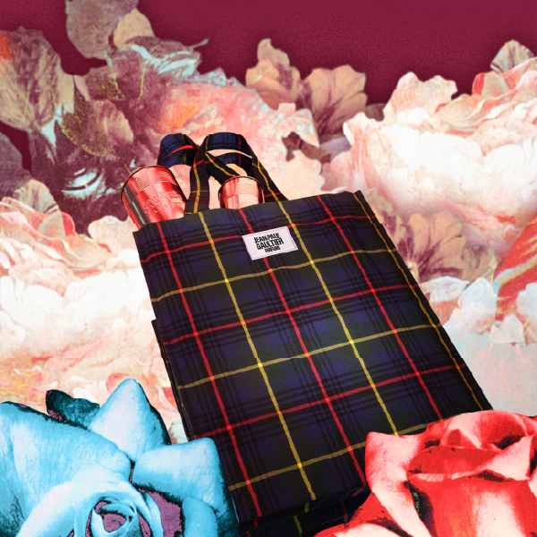 Tote bag Jean Paul Gaultier à motif tartan bleu, mis en scène dans un décor floral artistique