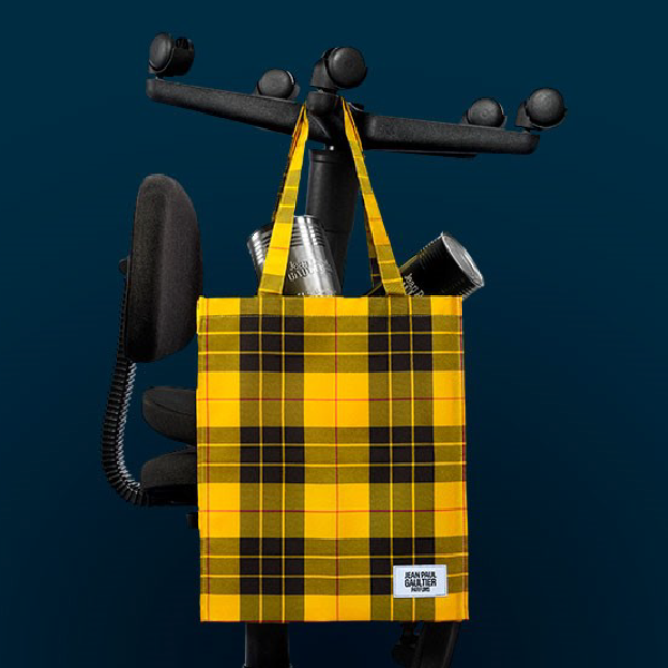 Tote bag Jean Paul Gaultier en tartan jaune, rempli de boîtes de parfum et suspendu à une chaise de bureau.