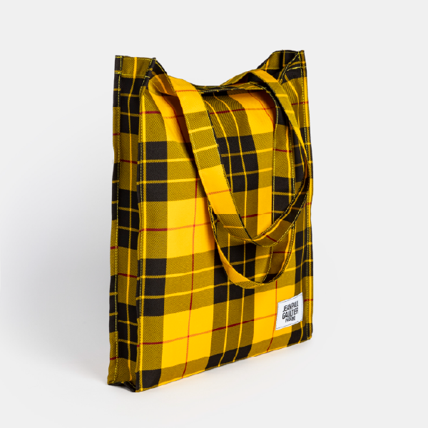 Vue de trois-quarts du tote bag Jean Paul Gaultier à motif tartan jaune, montrant sa forme et ses anses.