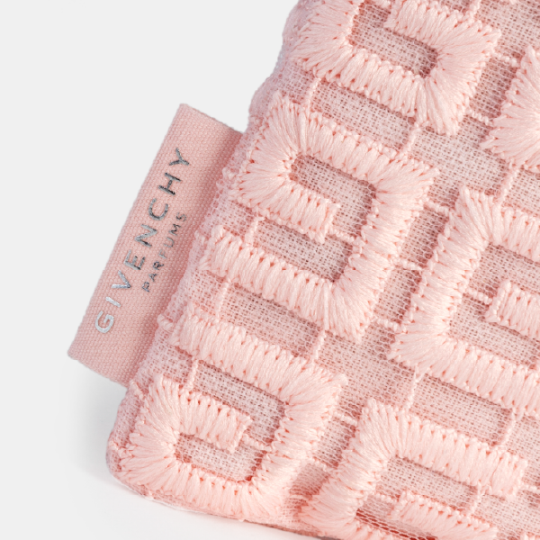 Gros plan sur l'étiquette en tissu rose siglée "GIVENCHY PARFUMS" en lettres argentées, attachée à la trousse en guipure rPET rose.