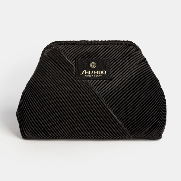 Vue de face de la trousse noire Shiseido en rPET plissé, avec son patch logo central et sa forme structurée.