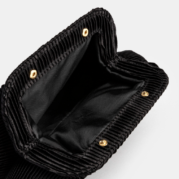Vue de l'intérieur de la trousse Shiseido ouverte, montrant la doublure noire et les boutons-pression dorés de fermeture.