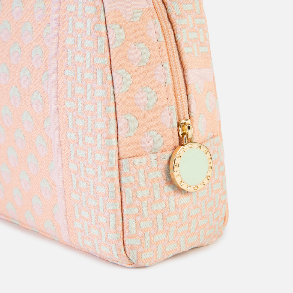 Gros plan sur le coin de la trousse Jacquard pêche, montrant la texture du tissu recyclé, la fermeture éclair dorée et le médaillon siglé Bulgari.