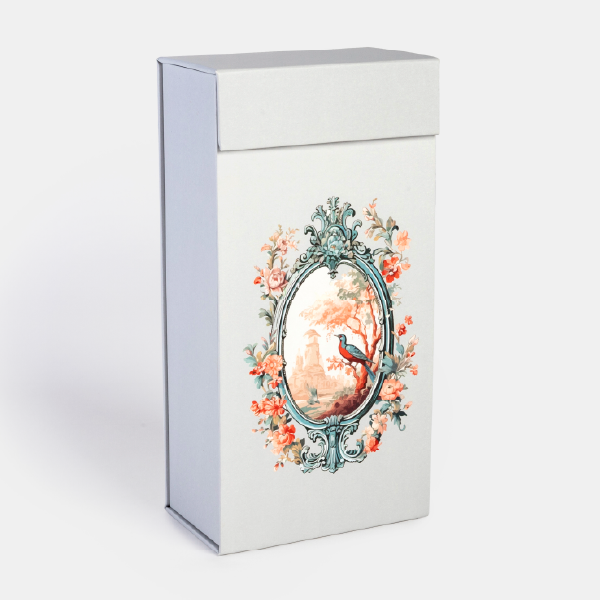 Le coffret pop-up vertical fermé, de couleur gris perle, avec une illustration de style baroque sur sa face avant.