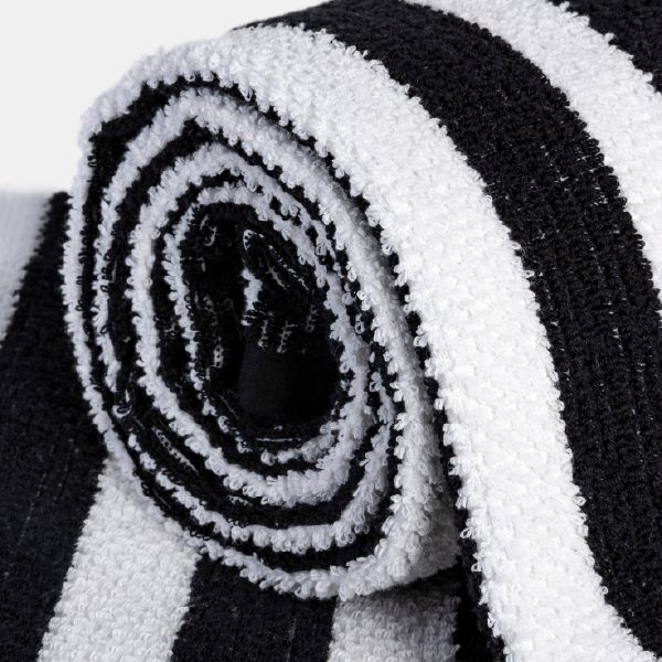 Gros plan sur la tranche d'une serviette éponge roulée, montrant la texture bouclée et le motif en spirale des rayures noires et blanches.
