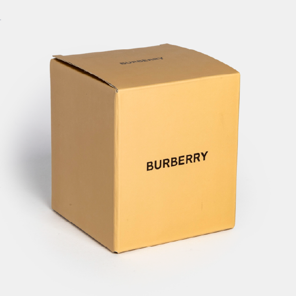 La boîte cubique de couleur beige signature pour la boule à neige Burberry, fabriquée en papier certifié FSC, avec le logo de la marque en noir sur le côté.