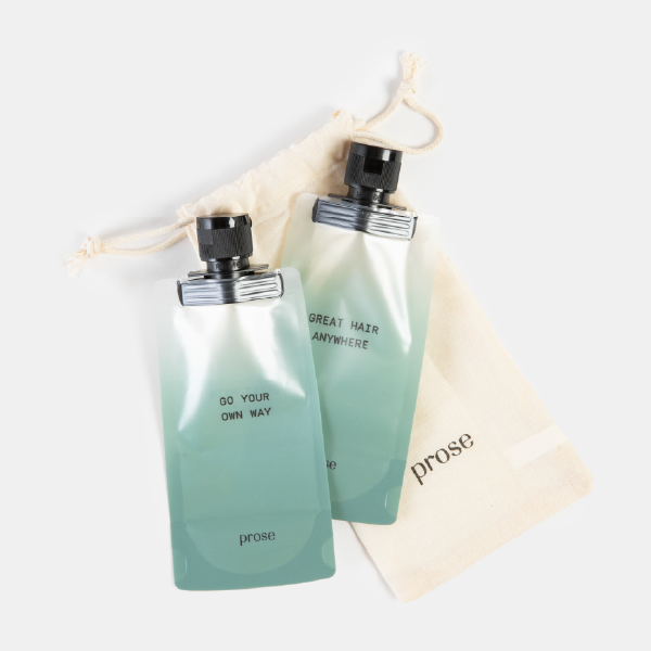 Le duo de bouteilles de voyage Prose présenté avec sa pochette de rangement en coton GOTS de couleur crème, sur fond blanc.
