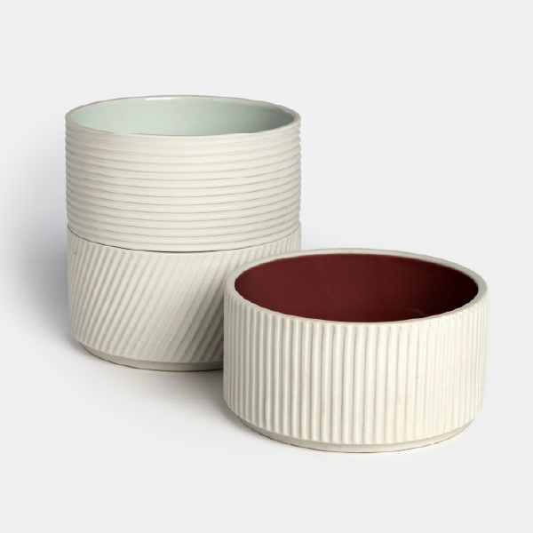 Deux coupelles en porcelaine empilées à côté d'une troisième, illustrant le design modulaire et la possibilité de les collectionner.