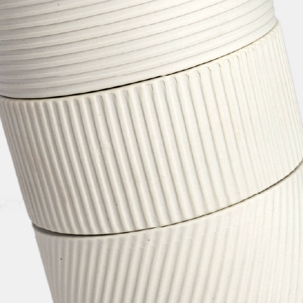 Gros plan sur la texture striée de trois coupelles en porcelaine biscuit empilées, montrant les différentes finitions en relief (verticales, diagonales, horizontales).