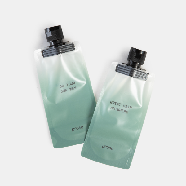 Deux bouteilles de voyage réutilisables de la marque Prose, avec un dégradé vert et les slogans "GO YOUR OWN WAY" et "GREAT HAIR ANYWHERE".