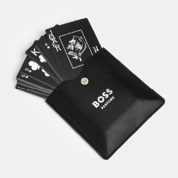 Le jeu de cartes noir BOSS Parfums glissé dans son étui, laissant apparaître plusieurs cartes dont le Joker et le Roi de Pique.