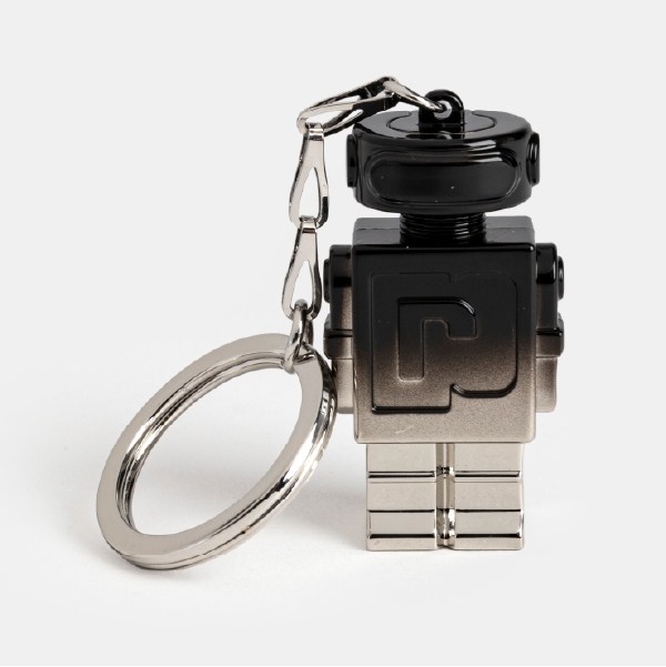 Porte-clé en métal en forme de robot Phantom de Paco Rabanne, montrant son dégradé de couleur du noir au gris métallisé et le logo 'R' sur le torse.