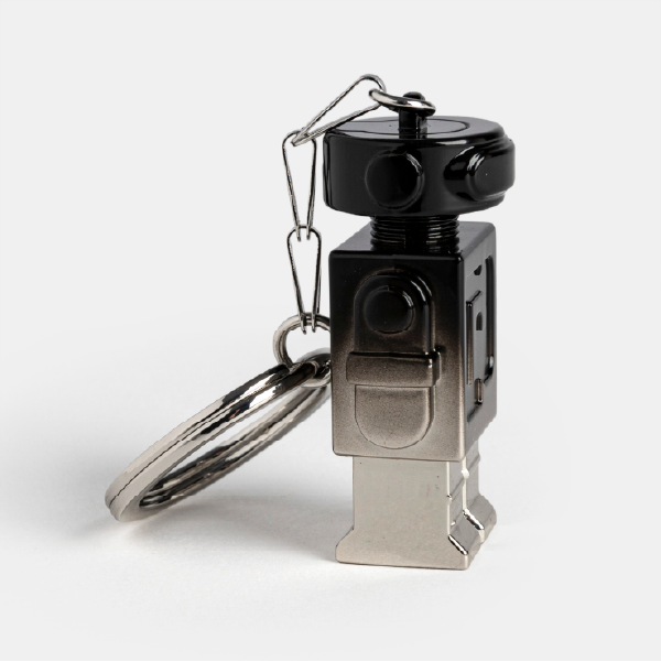 Vue de profil du porte-clé robot Paco Rabanne, mettant en avant la forme de sa tête et son corps en métal avec la finition dégradée.