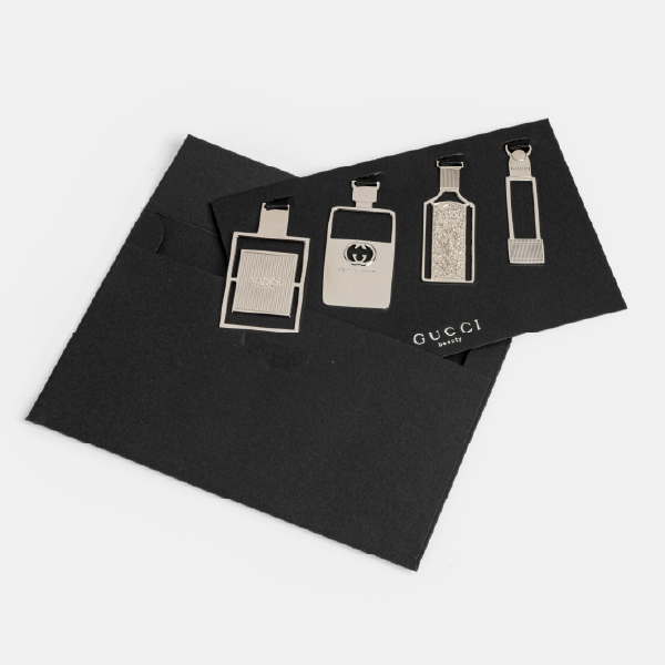 Le set de marque-pages Gucci sur son support, sortant de son coffret-enveloppe noir assorti.