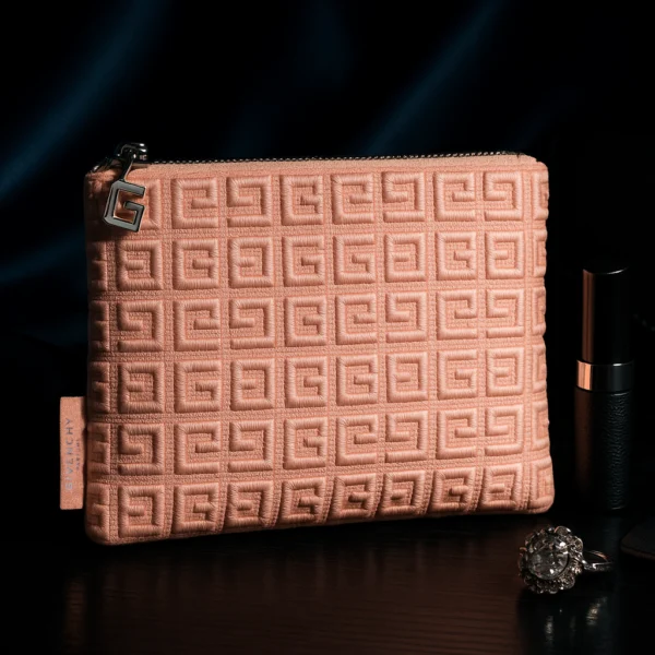 Trousse Givenchy Parfums en tissu rose texturé avec motif géométrique embossé et fermoir métallique siglé G, présentée comme accessoire élégant de luxe.